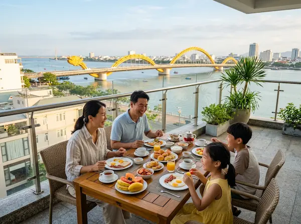 햇살이 부드럽게 비치는 다낭 한강 변 호텔 발코니에서 용다리를 배경으로 아침 식사를 즐기는 한국인 가족, 따뜻하고 평화로운 분위기